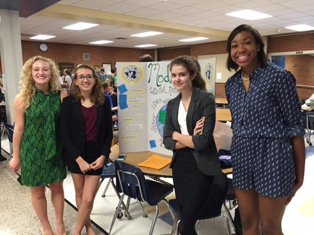 Model UN club leaders pose with poster, awaiting arrival of interested students