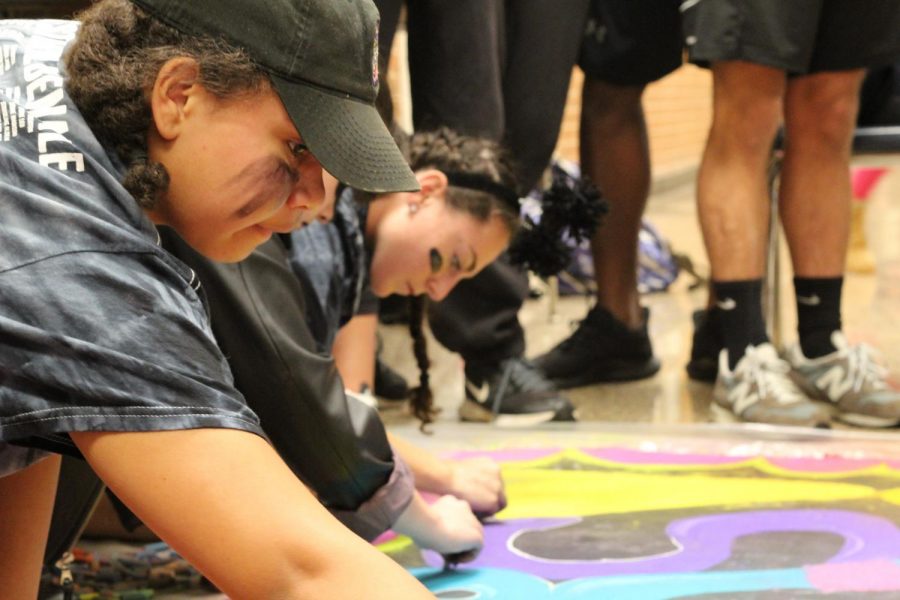 Deija Brooks and Kira Repich coloring the senior mural.