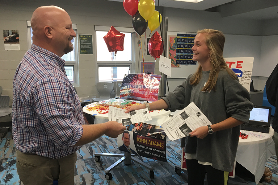 Savannah Wilson hands Mr. Mullins an informational flyer on candidate John Adams.